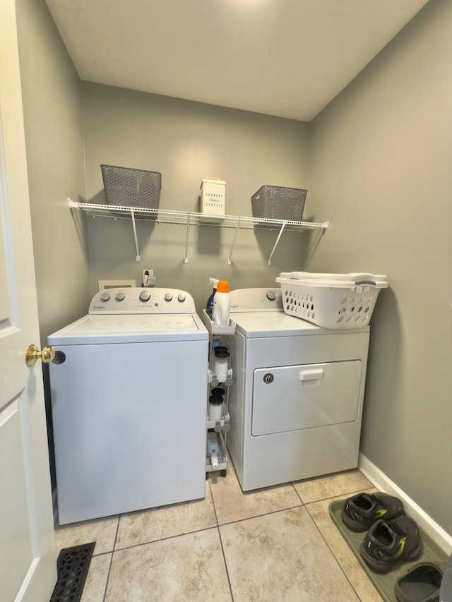 washroom featuring light tile patterned floors, laundry area, washer and dryer, and baseboards