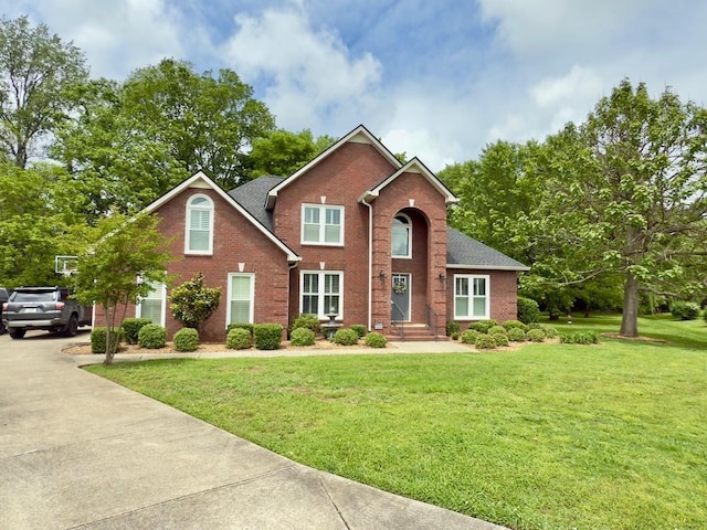 traditional-style house with concrete driveway, a front yard, and brick siding