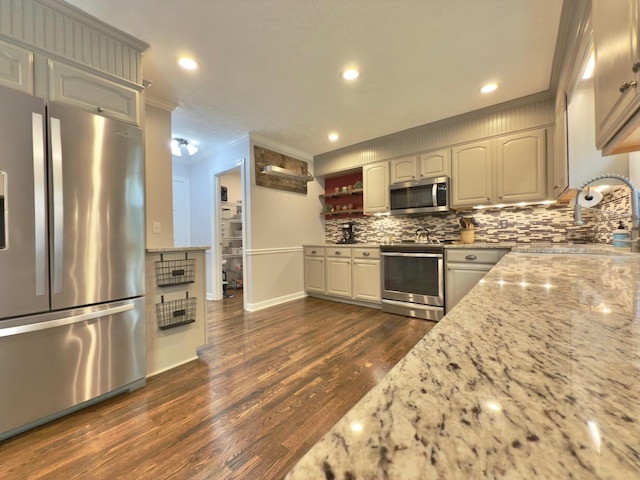 kitchen with light stone counters, dark wood-style flooring, backsplash, baseboards, and appliances with stainless steel finishes