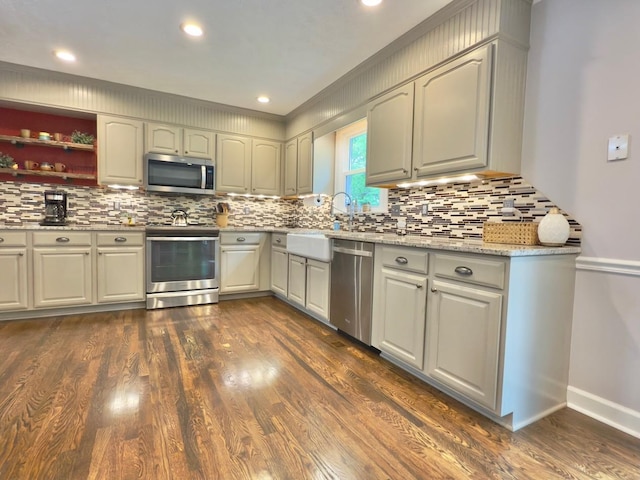 kitchen with a sink, stainless steel appliances, tasteful backsplash, and dark wood-type flooring