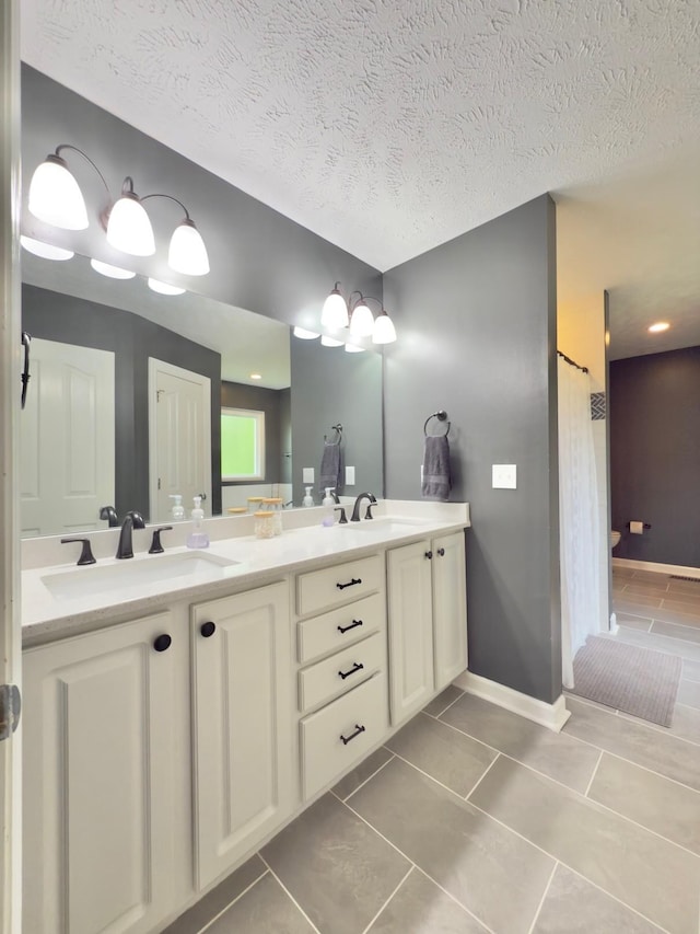 full bathroom featuring a textured ceiling, double vanity, and a sink