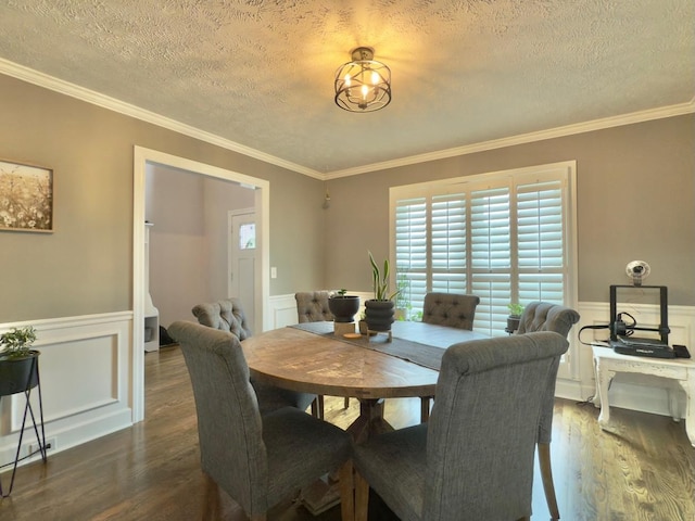 dining room with ornamental molding, a textured ceiling, and a wainscoted wall
