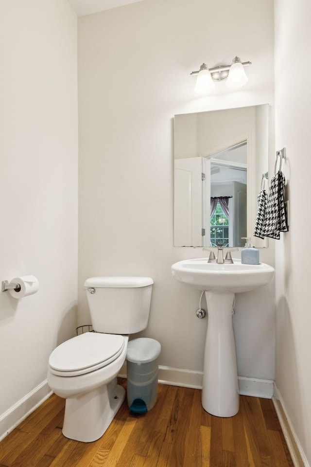 half bathroom featuring toilet, baseboards, and wood finished floors