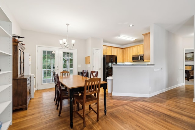 dining space with baseboards, a notable chandelier, light wood-style flooring, and french doors