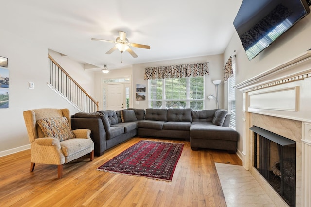 living room featuring a ceiling fan, stairway, baseboards, a high end fireplace, and hardwood / wood-style floors