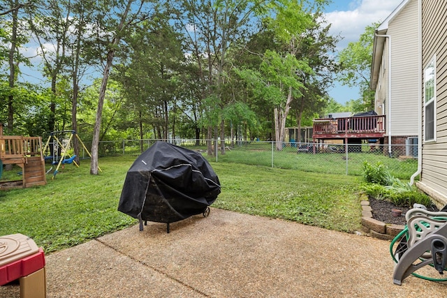 view of yard featuring a playground, a wooden deck, and a fenced backyard