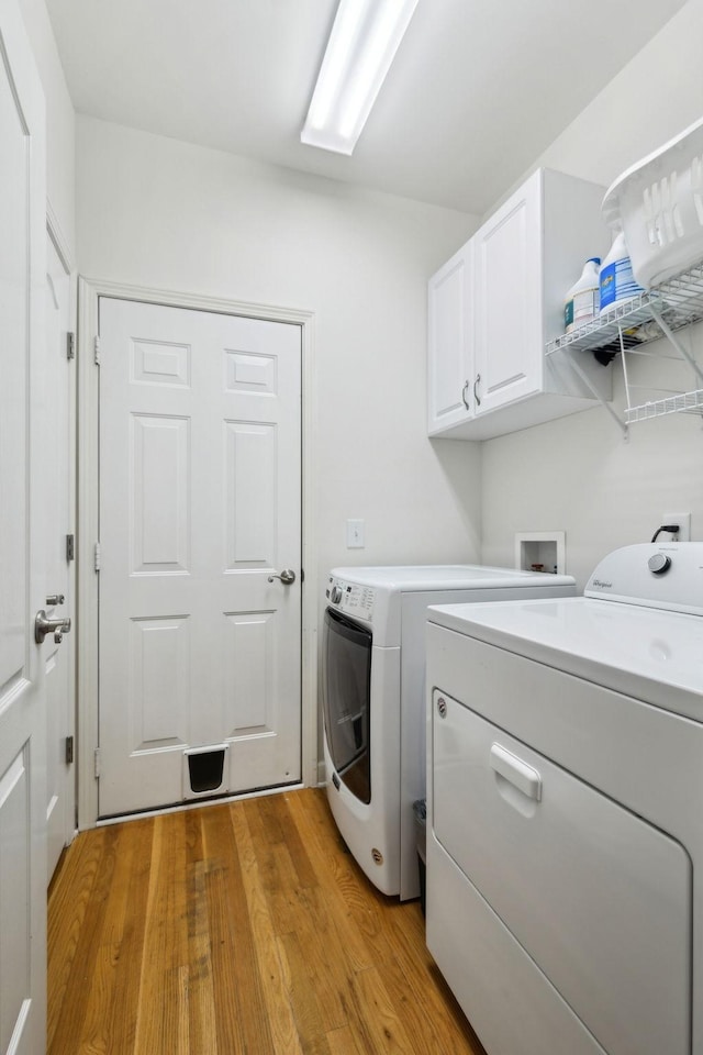 laundry area with cabinet space, light wood-style floors, and washer and dryer