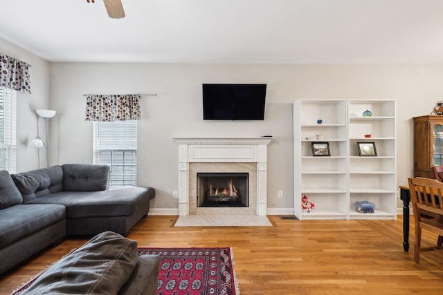 living room with a fireplace, baseboards, a ceiling fan, and wood finished floors
