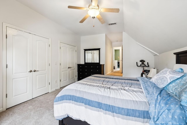 carpeted bedroom with vaulted ceiling, multiple closets, ceiling fan, and visible vents