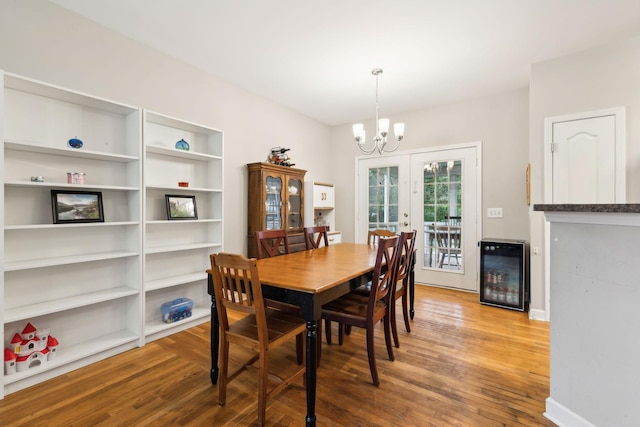 dining area featuring wine cooler, baseboards, an inviting chandelier, and wood finished floors