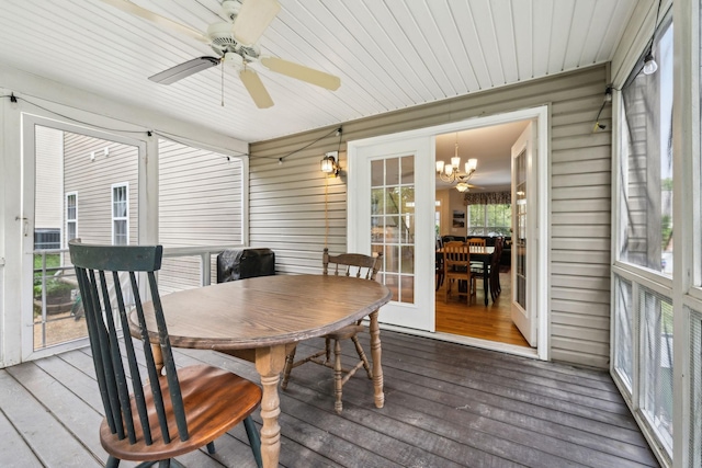 sunroom / solarium featuring outdoor dining area and ceiling fan with notable chandelier