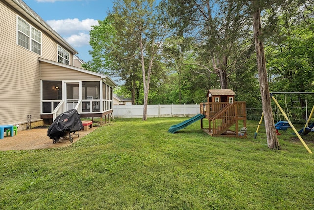 view of yard featuring a sunroom, a playground, and fence