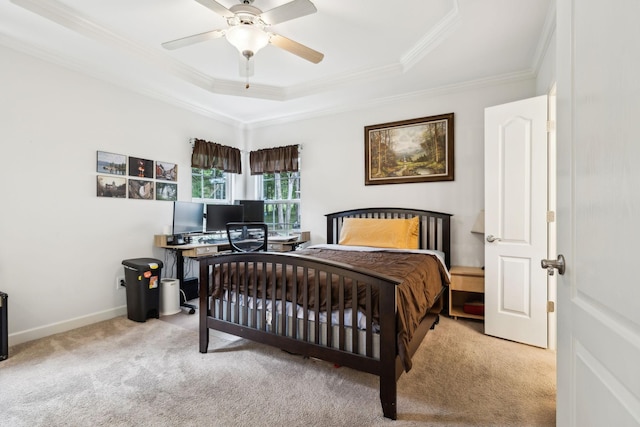 carpeted bedroom with a tray ceiling, crown molding, baseboards, and a ceiling fan