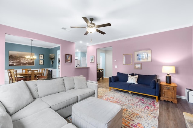 living room featuring ornamental molding, ceiling fan with notable chandelier, baseboards, and wood finished floors