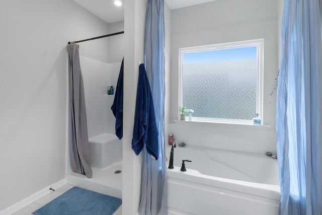 bathroom featuring a stall shower, baseboards, a bath, and tile patterned floors