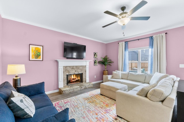 living area featuring a ceiling fan, ornamental molding, baseboards, and wood finished floors