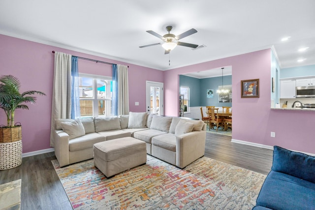 living area with ceiling fan with notable chandelier, wood finished floors, recessed lighting, crown molding, and baseboards