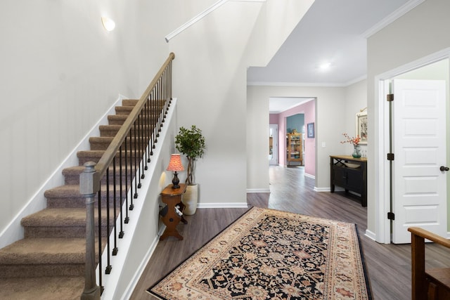 foyer entrance with dark wood-style flooring, stairs, and ornamental molding