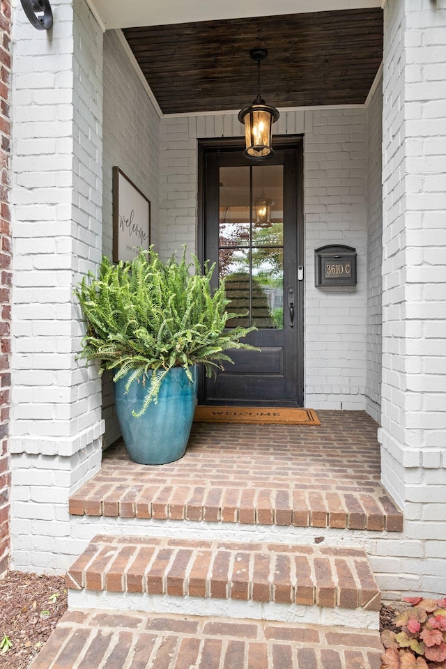 entrance to property featuring a porch and brick siding