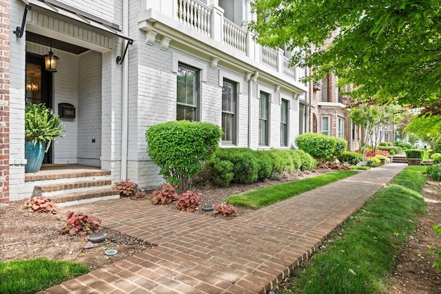 doorway to property featuring brick siding and a balcony