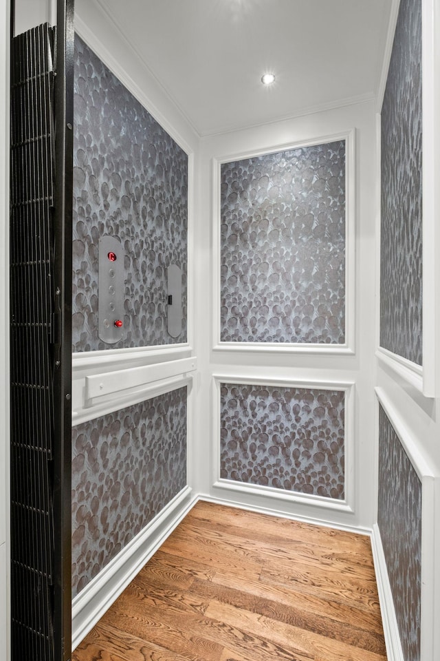 interior space featuring elevator, wood finished floors, and ornamental molding
