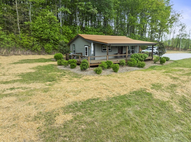 rear view of property featuring metal roof, a deck, and a lawn