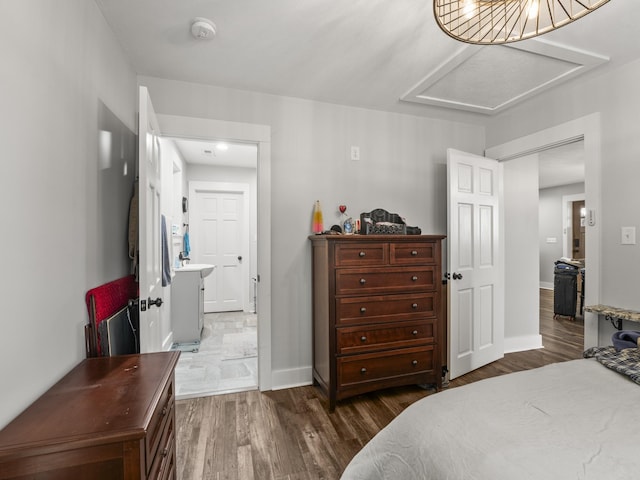 bedroom featuring attic access, baseboards, and dark wood finished floors