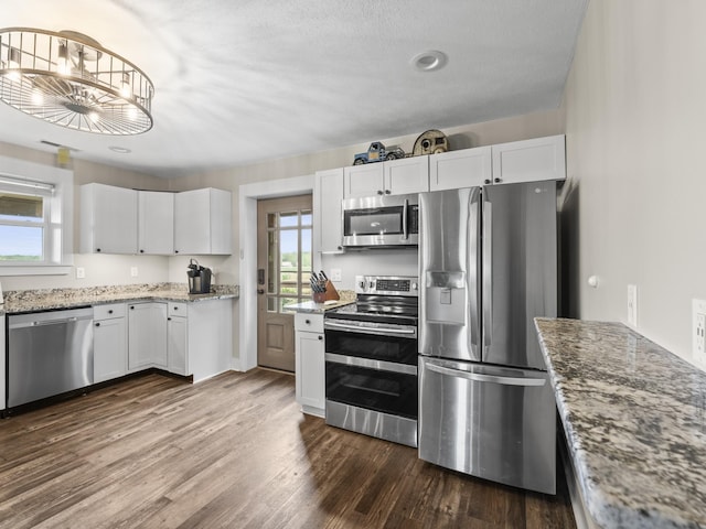 kitchen featuring white cabinets, appliances with stainless steel finishes, a healthy amount of sunlight, and dark wood-style floors
