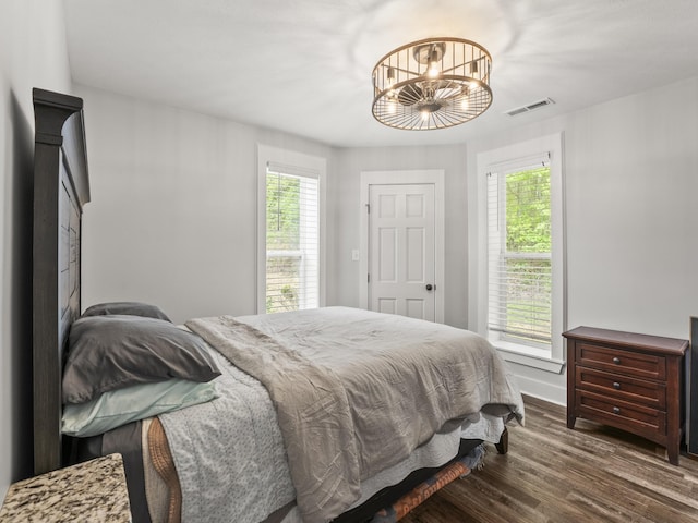 bedroom with visible vents, wood finished floors, baseboards, and a notable chandelier