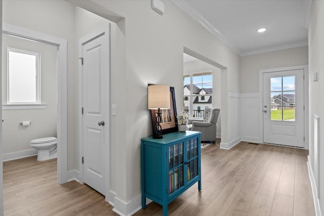 foyer entrance featuring baseboards, ornamental molding, and light wood-style flooring