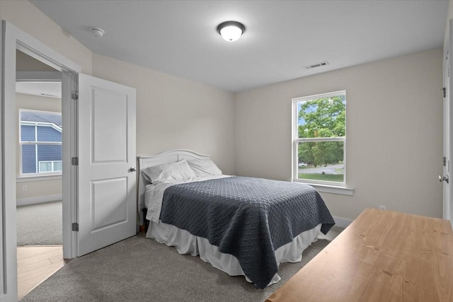 bedroom with visible vents, carpet, and wood finished floors
