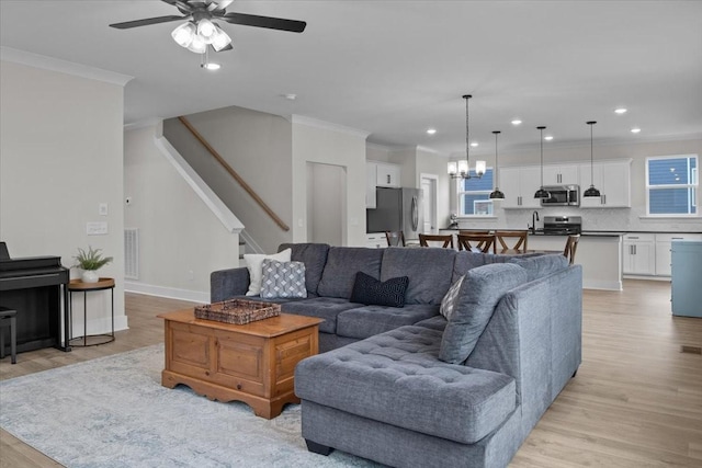 living area with recessed lighting, light wood finished floors, visible vents, ceiling fan with notable chandelier, and crown molding