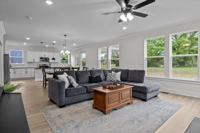 living area with light wood-type flooring, ornamental molding, a ceiling fan, and recessed lighting