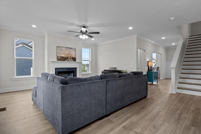 living area with crown molding, stairway, light wood-type flooring, a fireplace, and baseboards