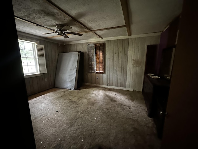 unfurnished bedroom with a textured ceiling, wood walls, and baseboards