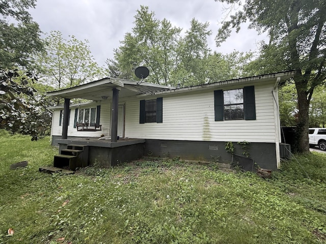rear view of property featuring covered porch, a yard, and crawl space