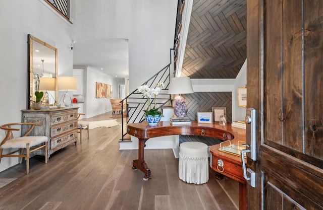 foyer entrance with wood finished floors, a high ceiling, and stairs