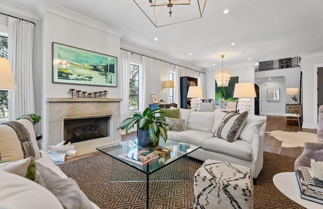living area with recessed lighting, a chandelier, crown molding, wood finished floors, and a fireplace