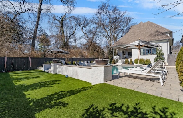 view of pool featuring a fenced in pool, exterior kitchen, a fenced backyard, a yard, and a patio area