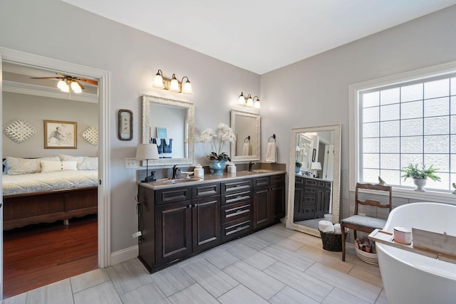 ensuite bathroom featuring double vanity, connected bathroom, a ceiling fan, a sink, and a freestanding bath