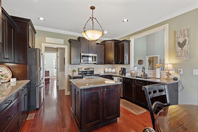kitchen featuring a sink, stainless steel appliances, light stone countertops, a kitchen island, and dark brown cabinets