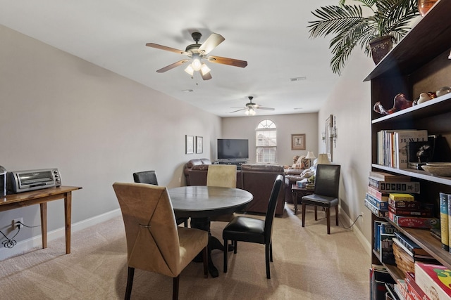 dining room featuring baseboards, light carpet, ceiling fan, and a toaster