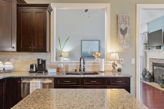 kitchen with stainless steel dishwasher, decorative backsplash, a sink, and dark brown cabinets