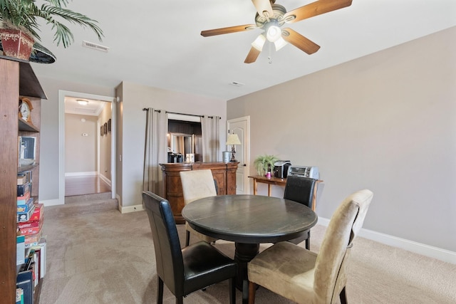 dining room with light carpet, baseboards, visible vents, and ceiling fan