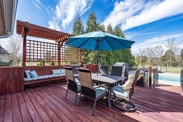 deck with outdoor dining area, fence, and a fenced in pool