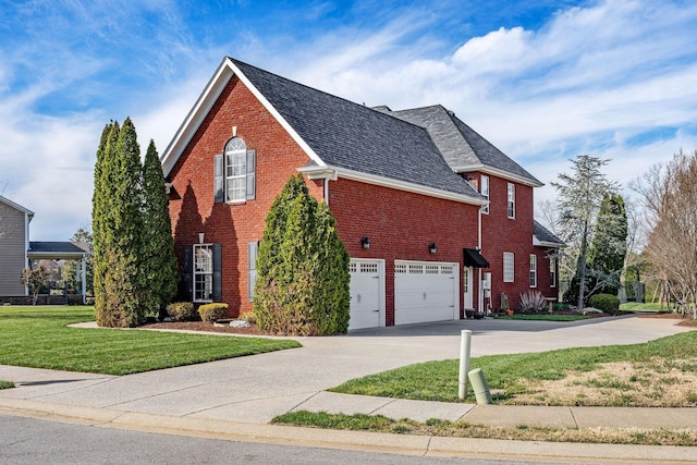 view of side of property with a yard, brick siding, an attached garage, concrete driveway, and roof with shingles