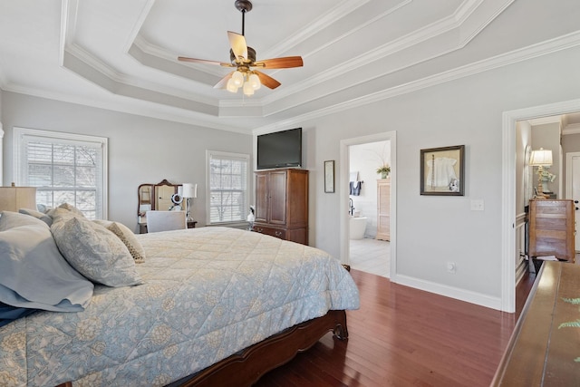 bedroom featuring baseboards, ornamental molding, connected bathroom, wood finished floors, and a raised ceiling