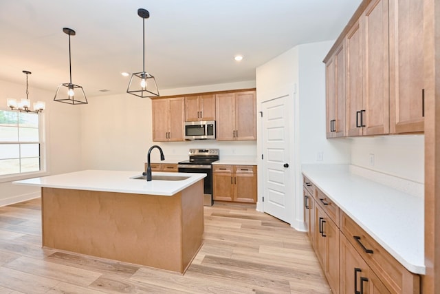 kitchen with a sink, stainless steel appliances, decorative light fixtures, light wood-type flooring, and light countertops