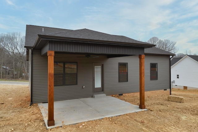 back of property with roof with shingles, a patio area, and crawl space
