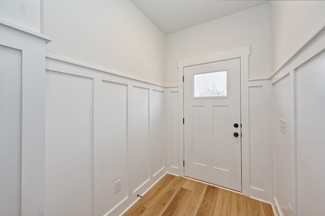 entryway featuring a wainscoted wall, a decorative wall, and light wood-type flooring